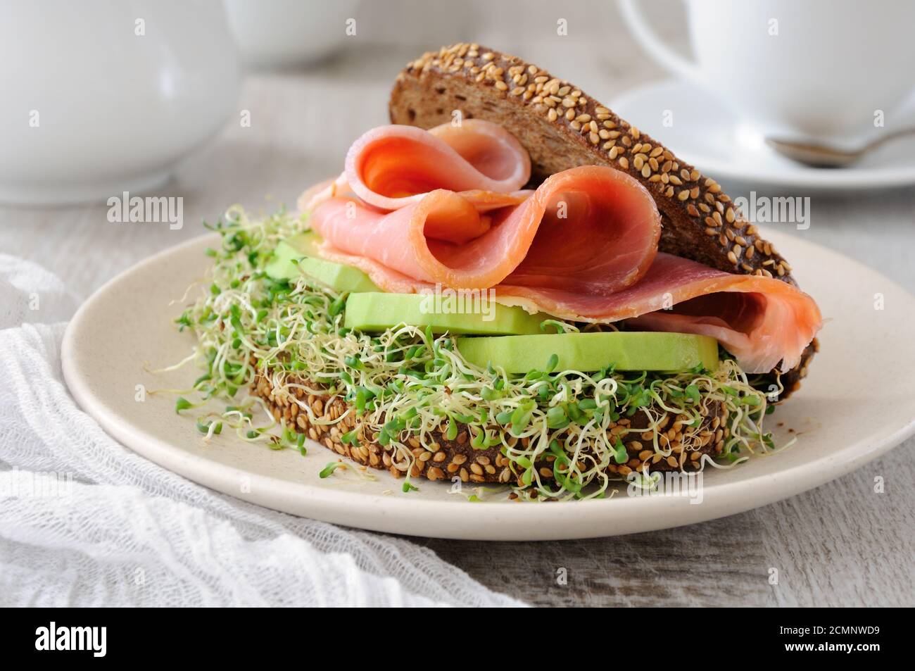 Sandwich of rye bread with cereals, slices of ham and avocado with