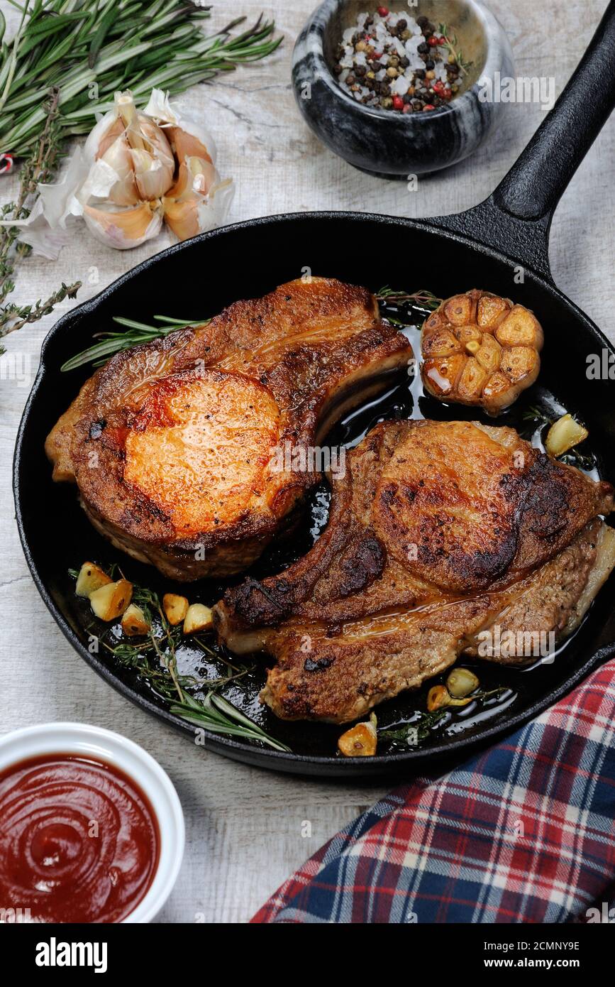 Roasted pork loin steak in a frying pan with tomato sauce and spices