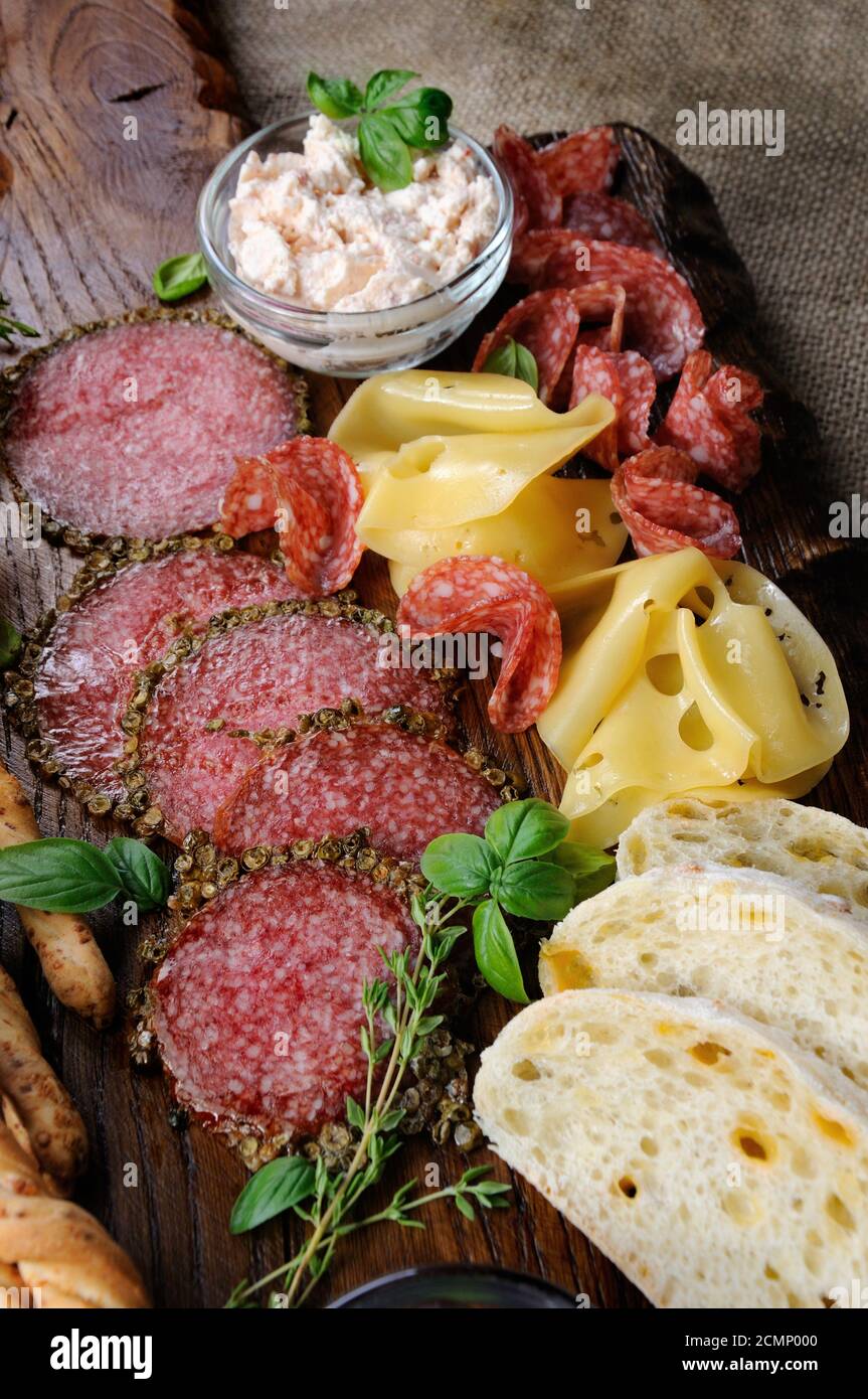 Dishes for snacks Antipasto with salami, slices of cheese, cheese pasta and ciabatta on a wooden bac Stock Photo