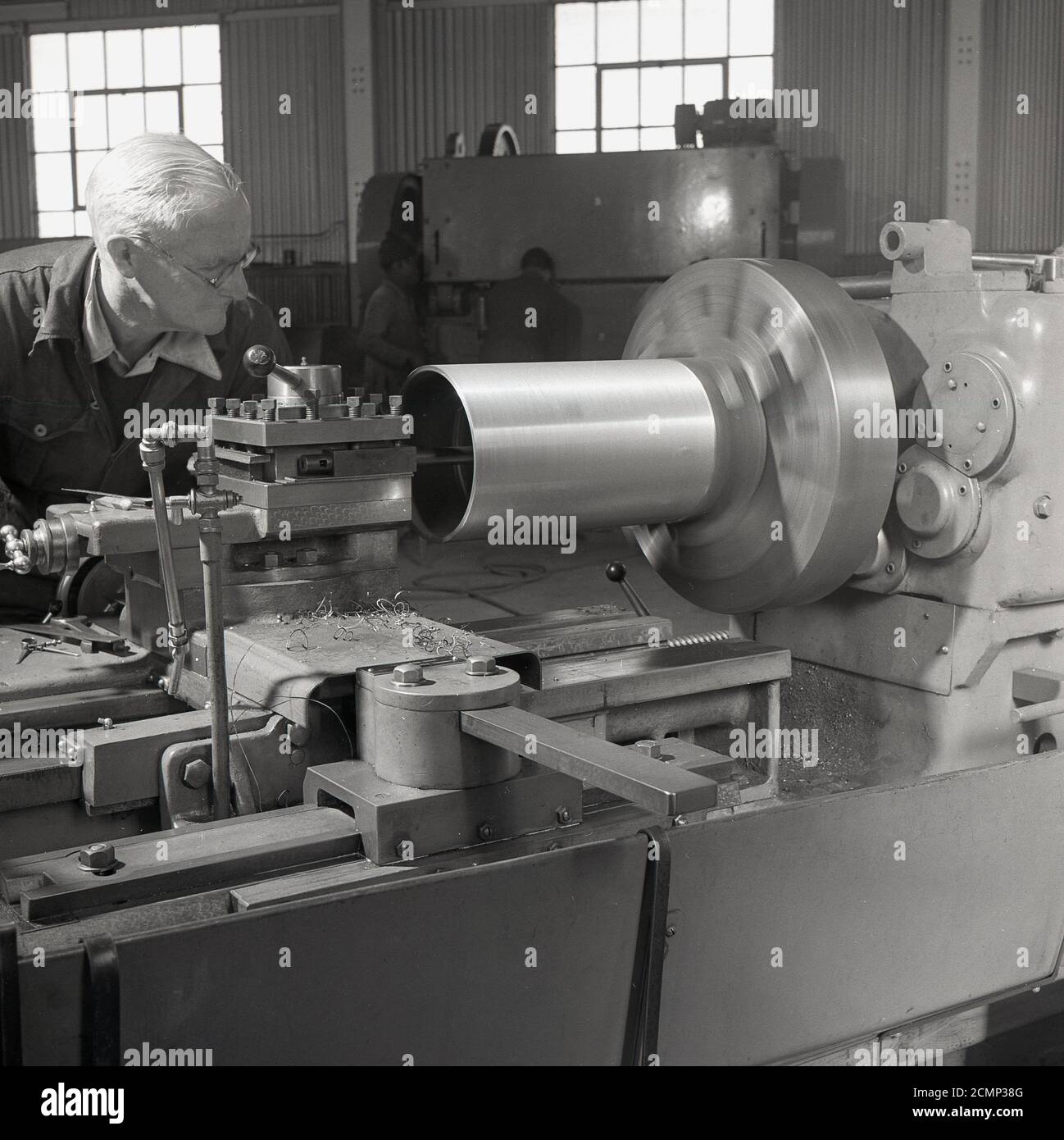 1950s, historical, elderly male worker using a precision engineering lathe, a machine tool for making metal parts for industry, England, UK. As be can be seen, the worker is not wearing any protective goggles or airmuffs, with health & safety in post-war Britain not what it later came. Stock Photo