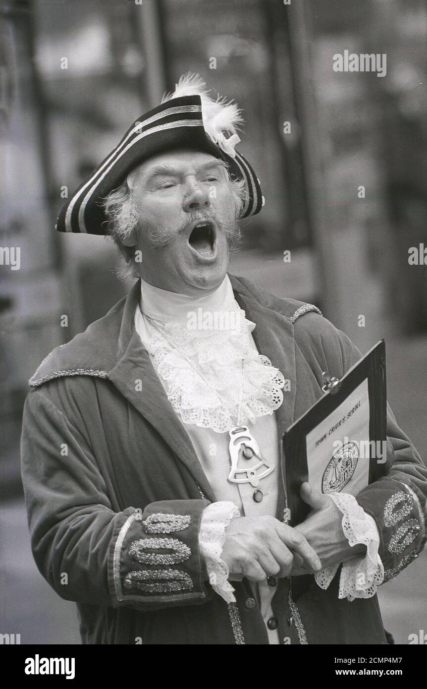 1987, a town crier in his costume and holding a scroll, making a public announcement, York, England, UK. The tradition dates back to medieval times where information from the town crier on new laws, royal decrees, births, plays, shops etc was called out in the centre of English towns so as many people could hear it and understand it. A town crier is all about the message, giving a public notice by loud proclamation and they still exist in many English towns today. Stock Photo