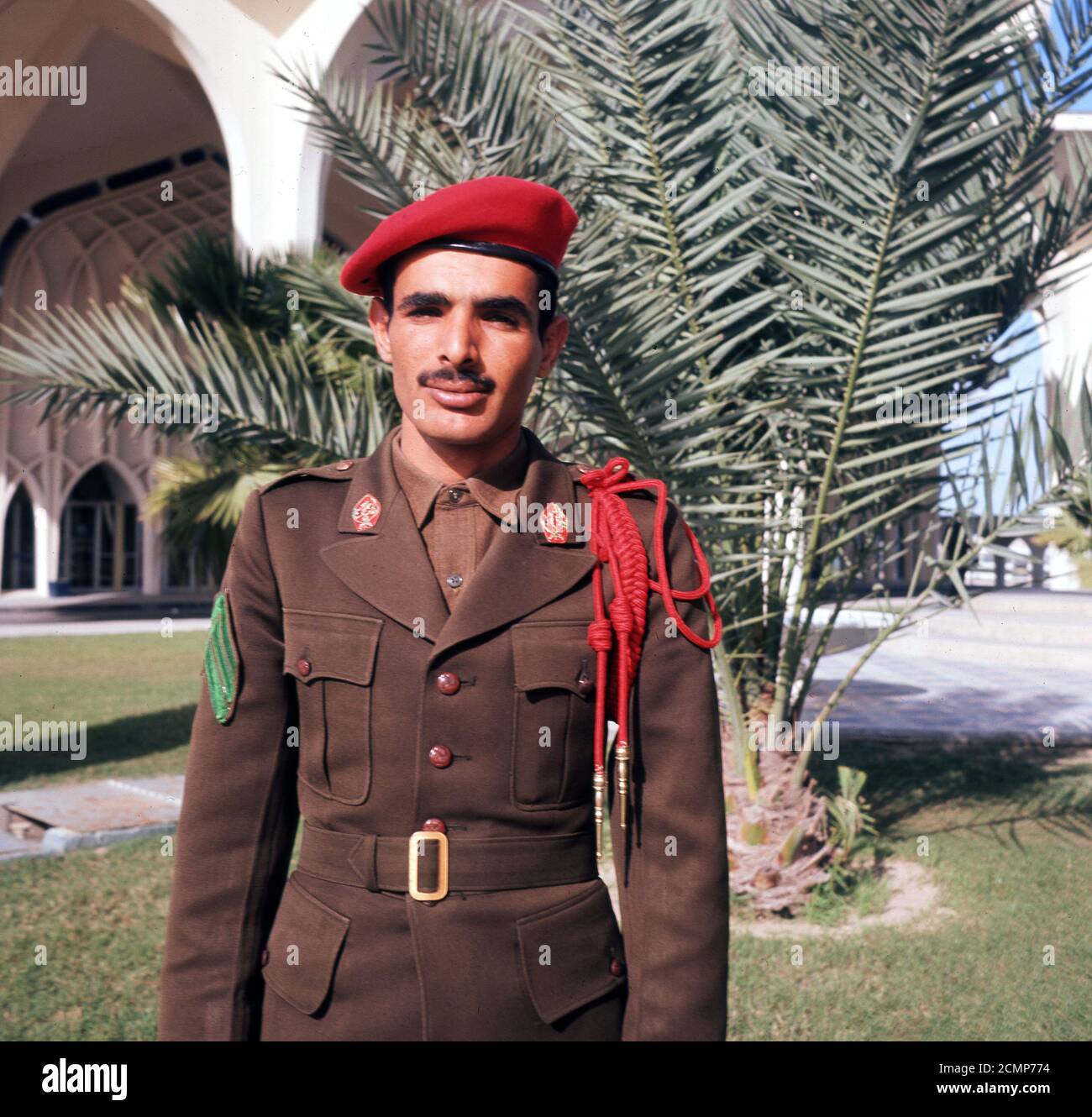 1960s, Saudi Arabia, Dhahran, Saudi National Guard or Police Sergeant standing for a picture in his brown or khaki coloured uniform and red beret, a colour influenced by British and US army models.  In 2015, the traditional kahki was replaced with new black uniforms. Stock Photo