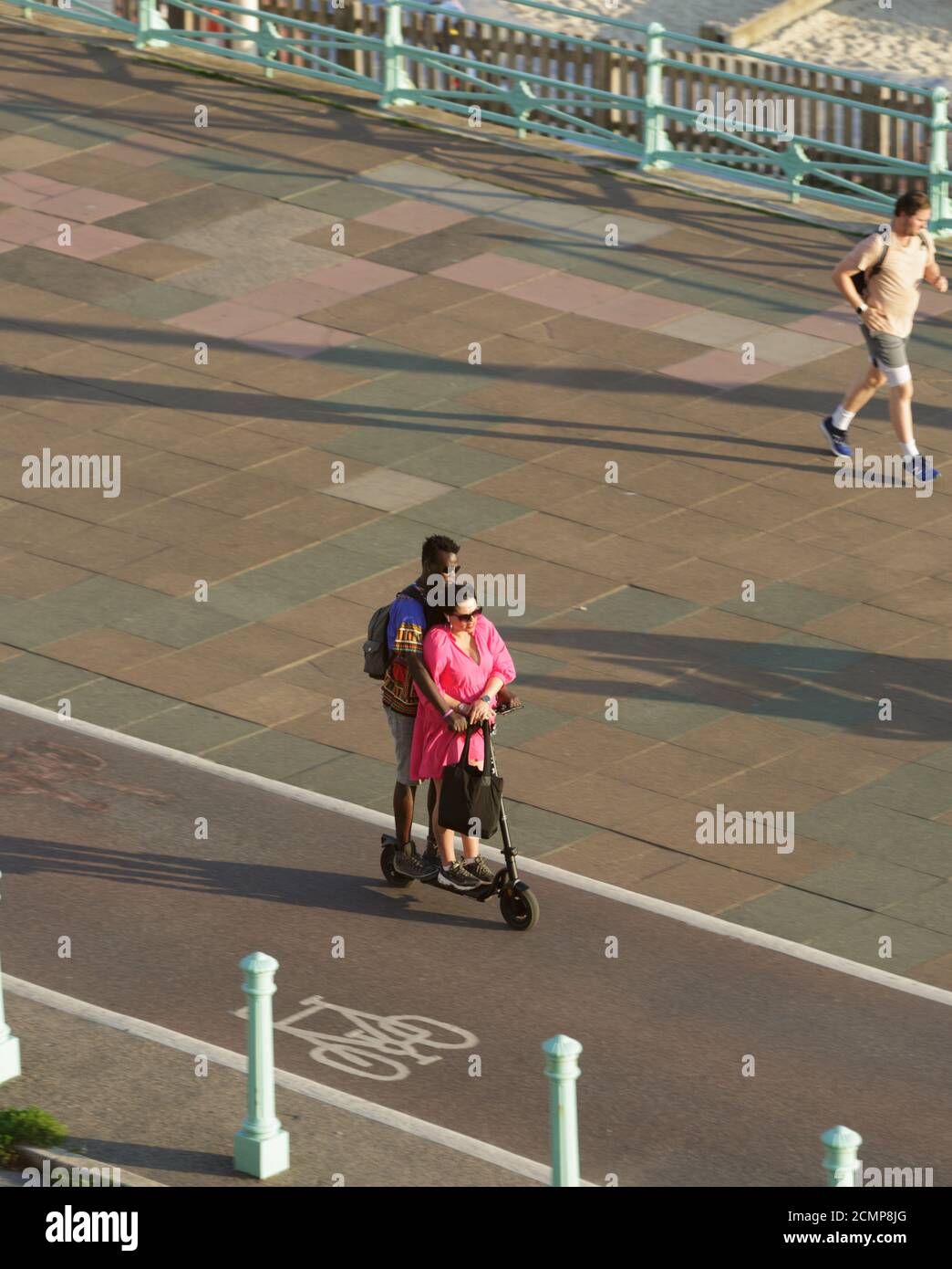 Couple riding on an electric scooter in a cycle lane. Unsharpened Stock Photo