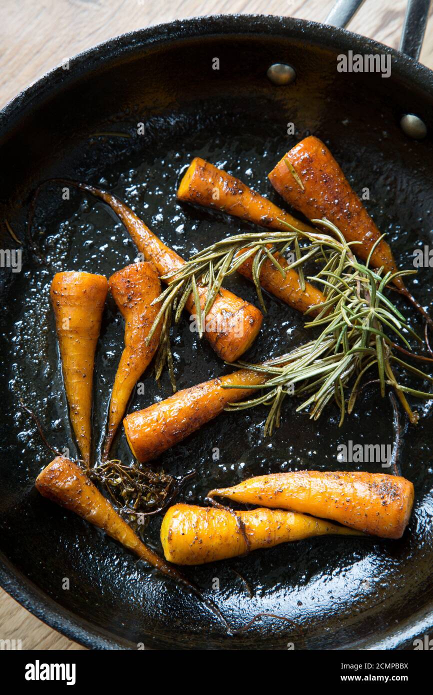Spiced carrots with rosemary in skillet Stock Photo
