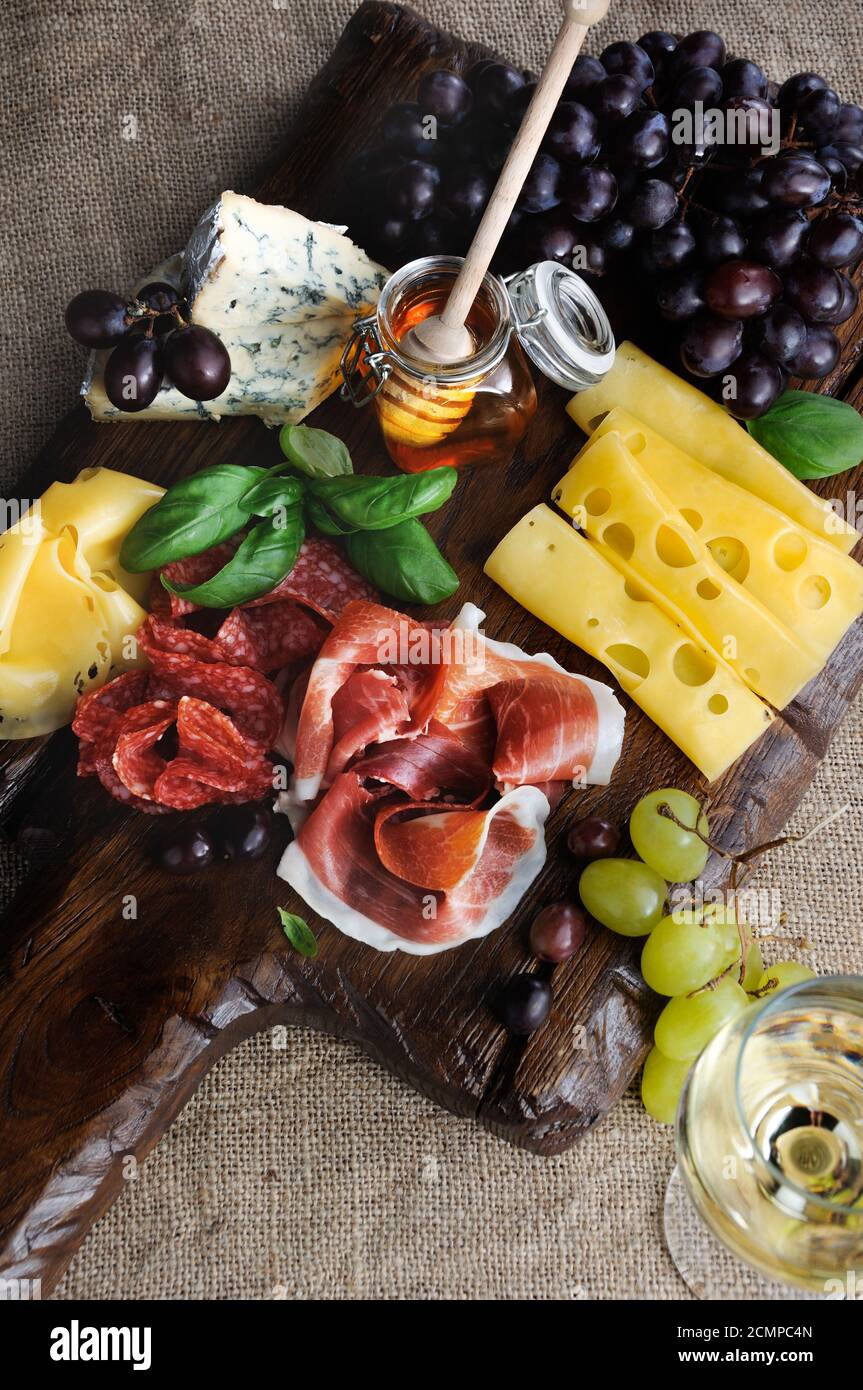 Antipasto catering platter with jerky bacon,  prosciutto, salami, cheese    and grapes on a wooden b Stock Photo