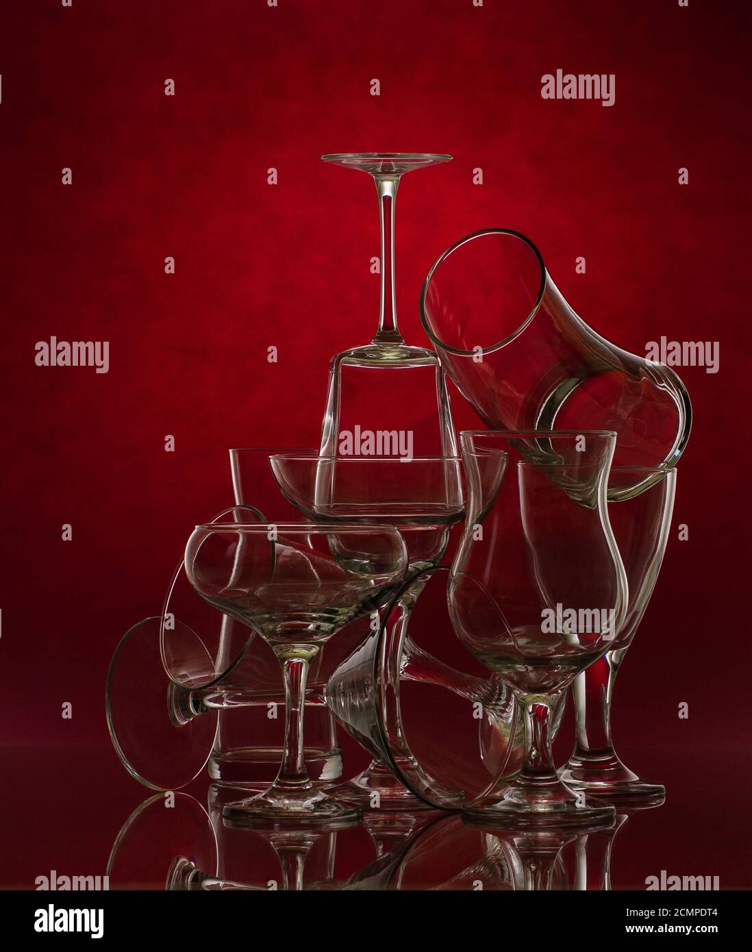 Composition of glass glasses of different shapes on a red background. Art photography. Stock Photo
