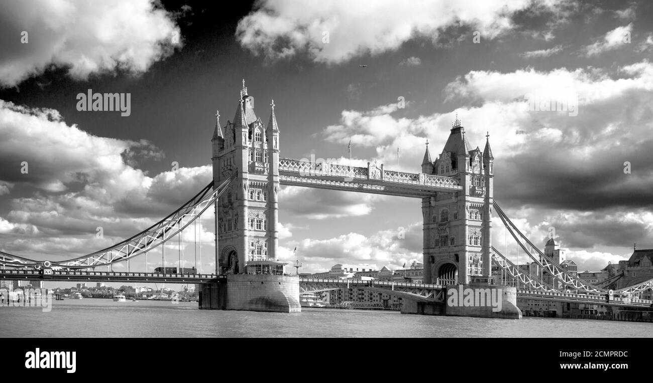 Landscape view of the iconic Tower Bridge which spans the River Thames with a dramatic cloudscape sky in black & white Stock Photo
