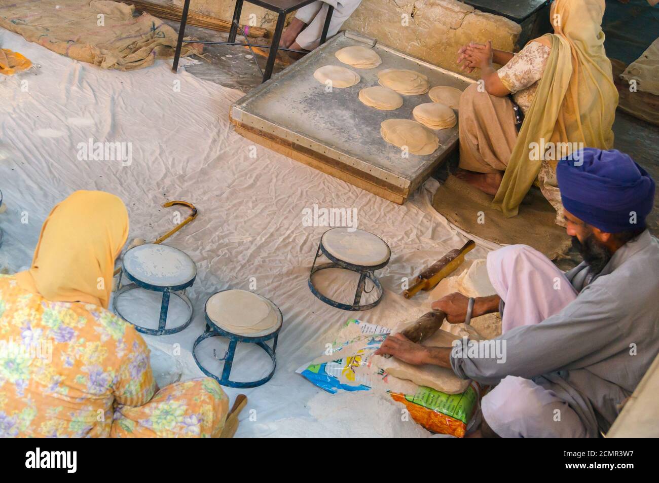 Amritsar, India - November 21, 2011: Unknown Indian people cook national bread for a free meal for pilgrims. Golden Temple in Amritsar, Punjab, India. Stock Photo