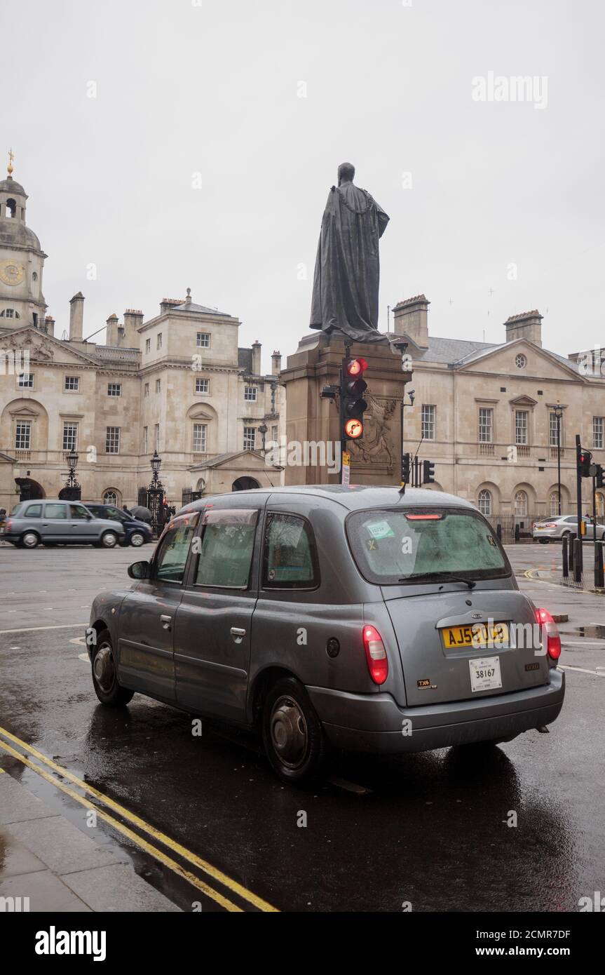 A Licensed London Taxi stopped at a red light traffic signal opposite Horse Guards Parade on a dreary wet day.  Taxis are a popular way to travel Stock Photo