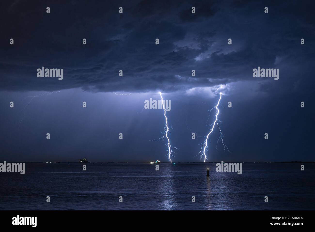 Storm cloud with double lightning strike in the water of a river Stock Photo