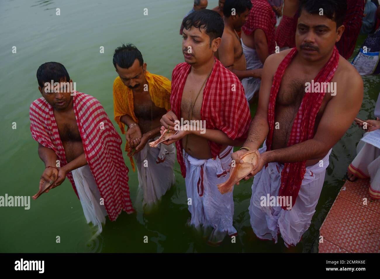 Indian Hindu devotees perform Tarpan, a ritual to pay obeisance to one's forefathers on the last day for offering prayers to ancestors called Pitri Tarpan. In Hindu mythology, this day is also called 'Mahalaya' and described as the day when the Gods created the ten armed Goddess Durga to destroy the demon king Asur who plotted to drive out the gods from their kingdom. The five-day period of worship of Durga, is attributed as the destroyer of evil. Agartala, Tripura, India. Stock Photo