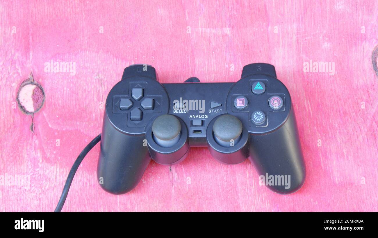 Joystick, black color game controller with controllers, with multiple buttons, used in computer video games, simulators and notebook, red wooden backg Stock Photo
