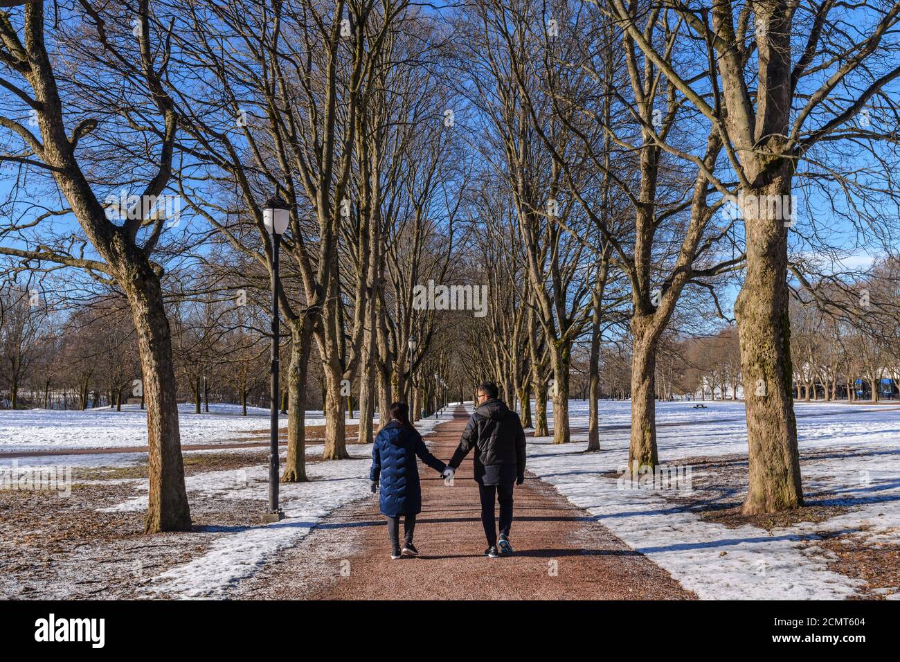 Love couple holding hands walking on the walk path in winter landscape with snow and dry tree Stock Photo