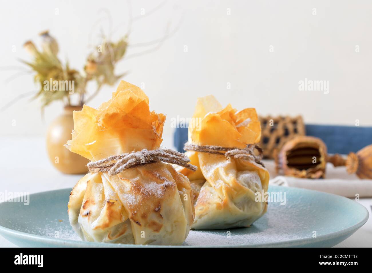 Plum and poppy seeds phyllo purses on a white wooden, delicious vegetarian dessert on a white wooden table. Stock Photo