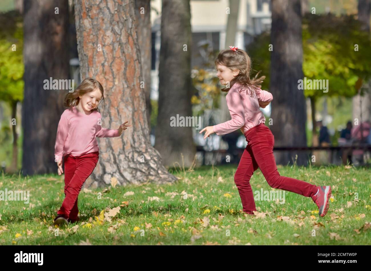 Two little sisters has fun outdoors in the park on a warm autumn day. The concept of a happy carefree childhood. Stock Photo