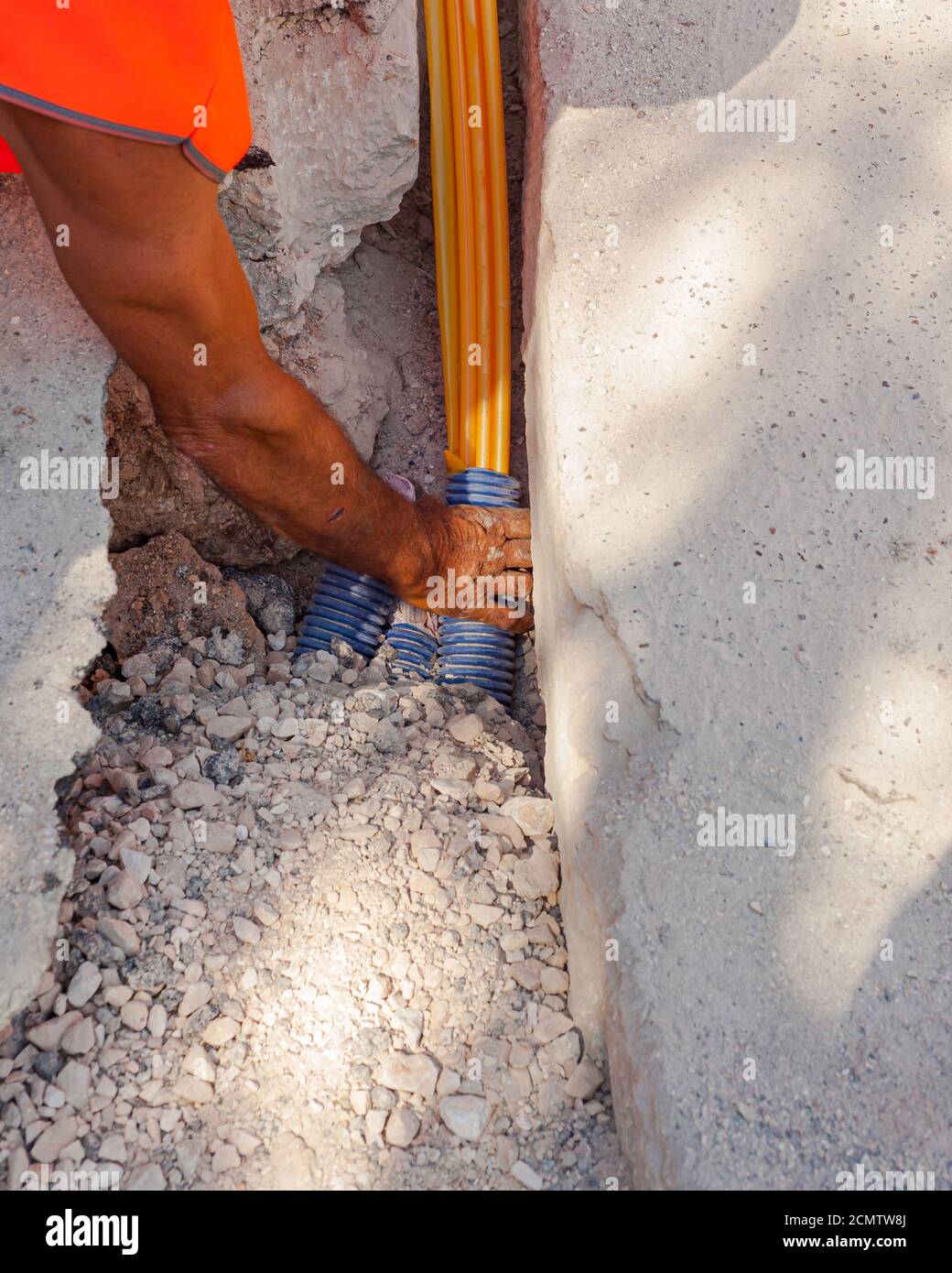Worker inserts fiber optic cables buried in a micro trench Stock Photo ...