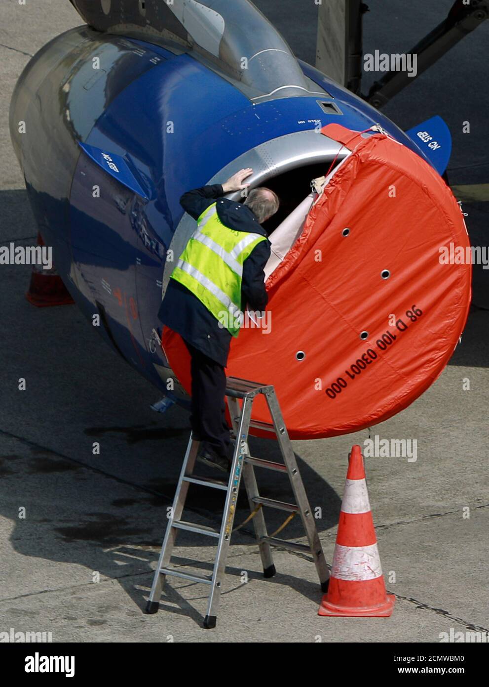 A worker removes a turbine cover at a British Airways plane at Berlin's Tegel airport April 20, 2010.  European airports made tentative steps toward resuming flights on Tuesday after five days cut off from global air traffic by a huge ash cloud, but much airspace stayed closed after reports of a new plume. REUTERS/Thomas Peter (GERMANY - Tags: TRANSPORT) Stock Photo