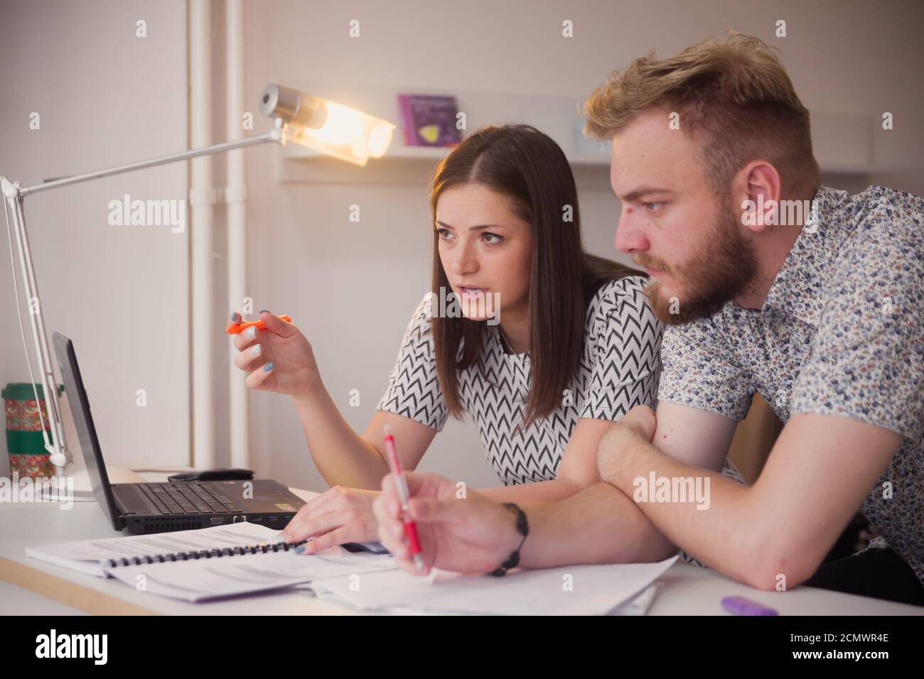 two people, studying together, seriously discussing project or learning. Stock Photo