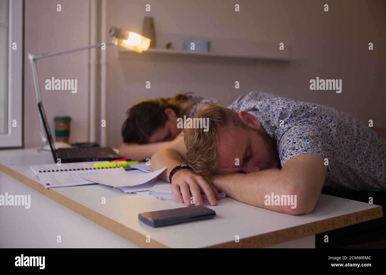 two students or coworkers, sleeping on table, exhausted from studying. Stock Photo