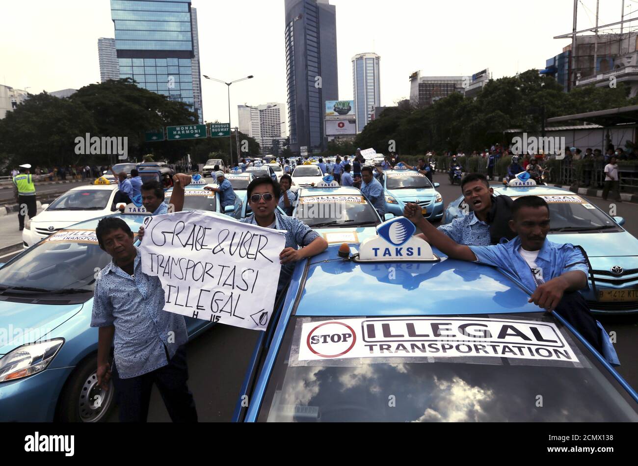 Taxi drivers stand beside a taxi during a protest rally against 