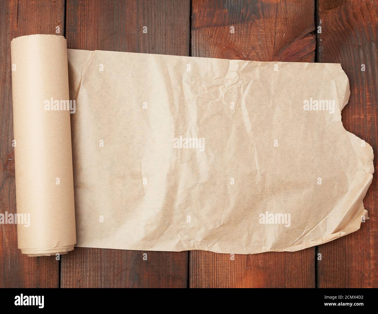 roll of untwisted brown paper on a wooden surface from old boards Stock Photo
