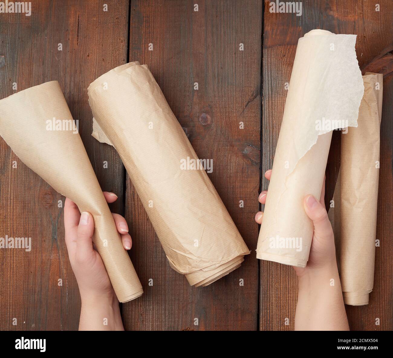 four rolled rolls of brown parchment paper on a wooden surface Stock Photo