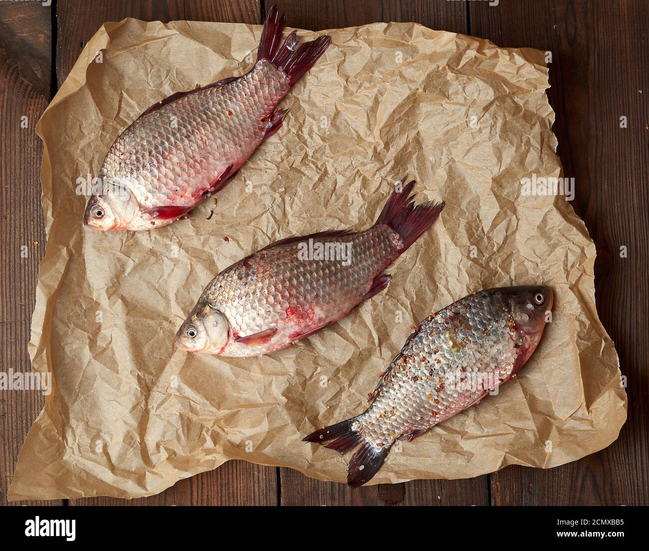 Paper Scale Fush whole fresh crucian fish with scales on a crumpled brown piece of paper ...