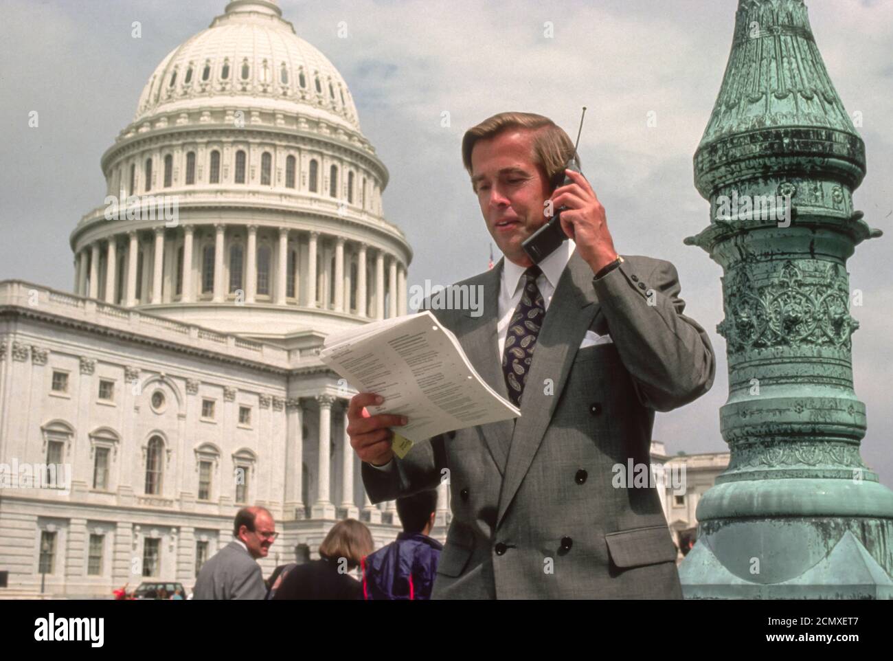 WASHINGTON, DC, USA - Lobbyist with mobile phone in front of U.S. Capitol building 1990s. Stock Photo