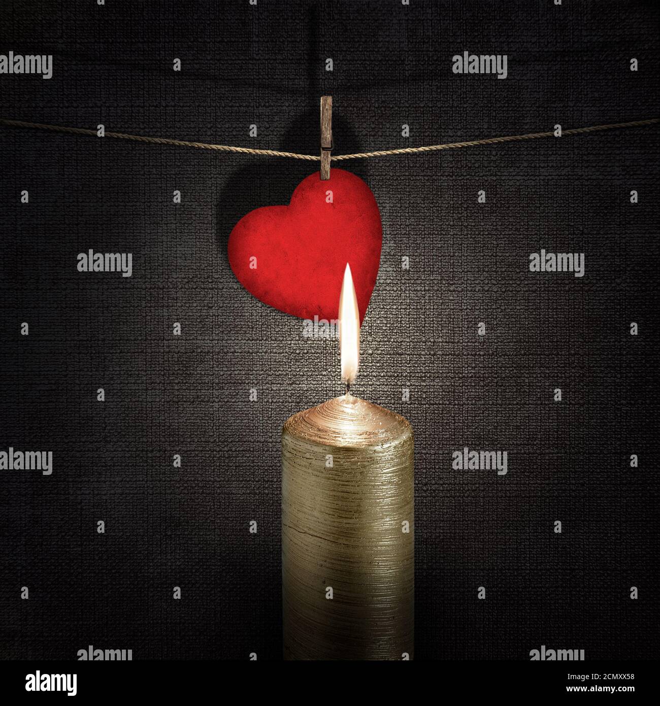burning candle and red paper heart on a rope over vintage embossed dark backgrounds Stock Photo