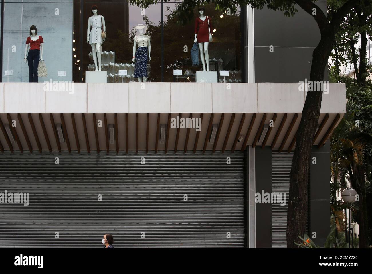 A woman wearing a face mask passes by a closed mall that reduced its opening hours amid the coronavirus disease (COVID-19) outbreak in Sao Paulo, Brazil March 19, 2020. REUTERS/Rahel Patrasso Stock Photo