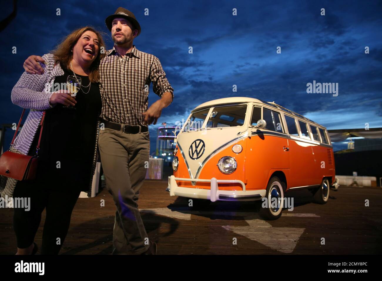 Guests pose in front of an old Volkswagen camper van at an event to