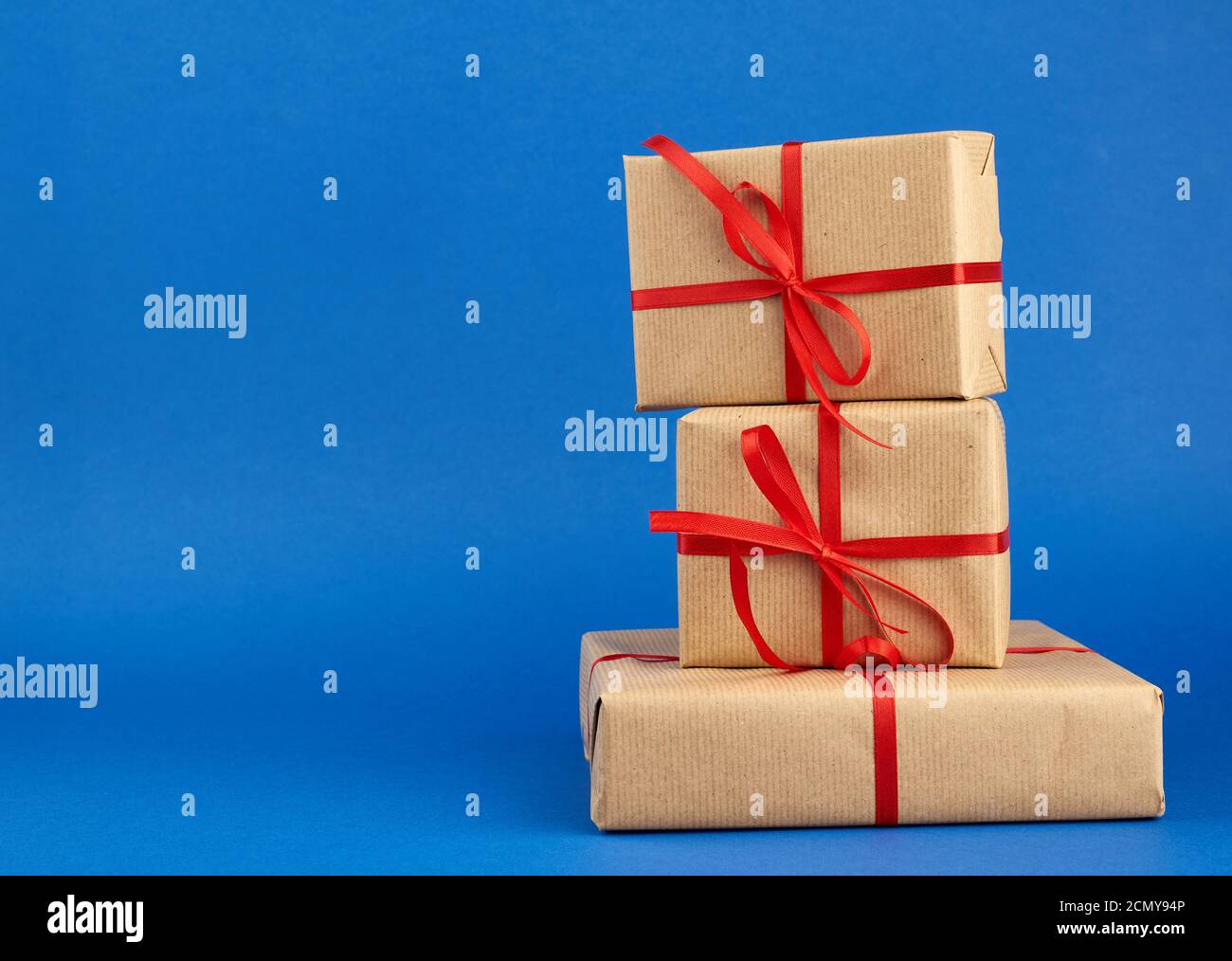 stack of boxes wrapped in brown paper and tied with a red bow, gifts on