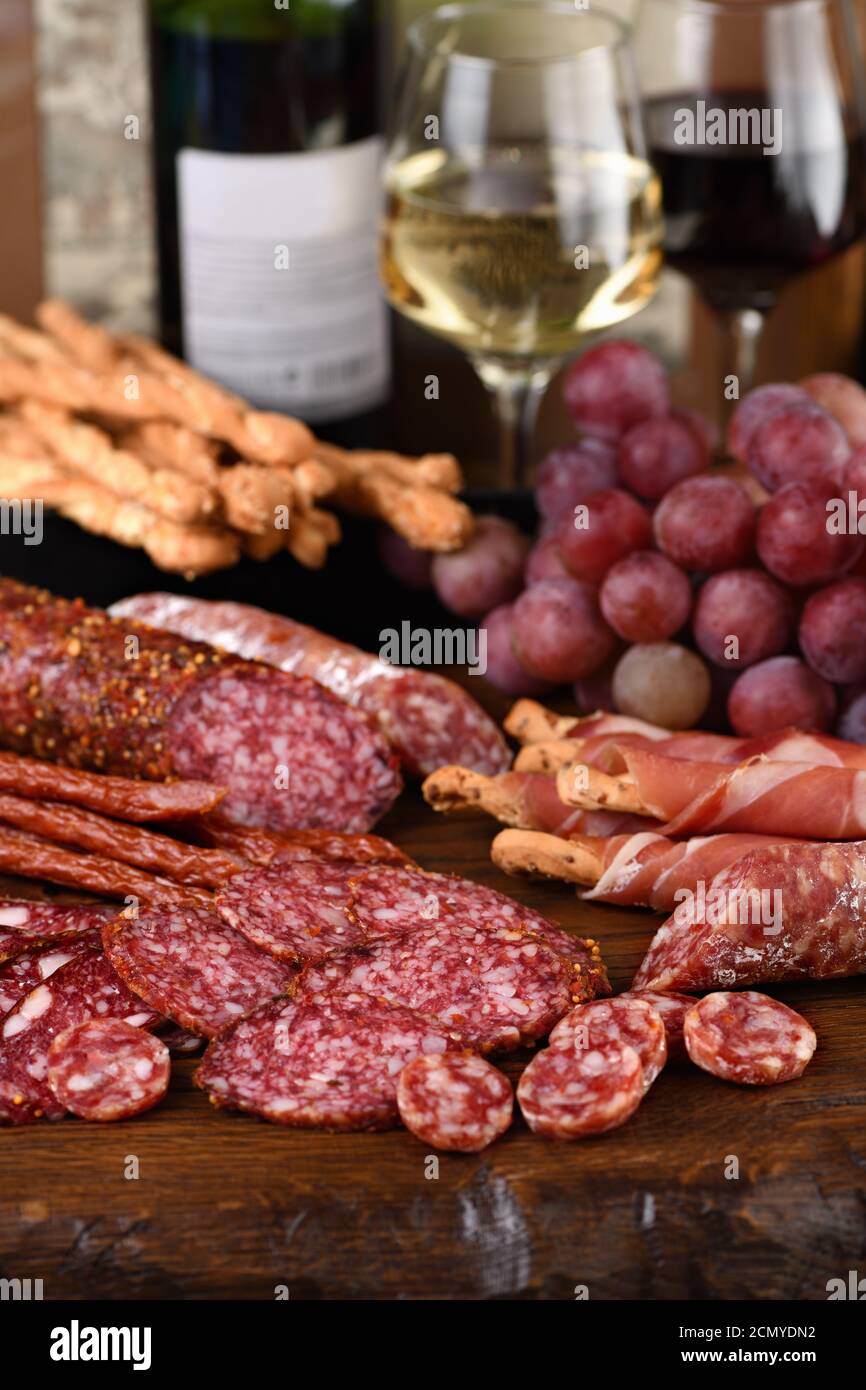 Antipasto. Dish with sausage, dried ham, salami, crispy grissini with grapes. A meat appetizer