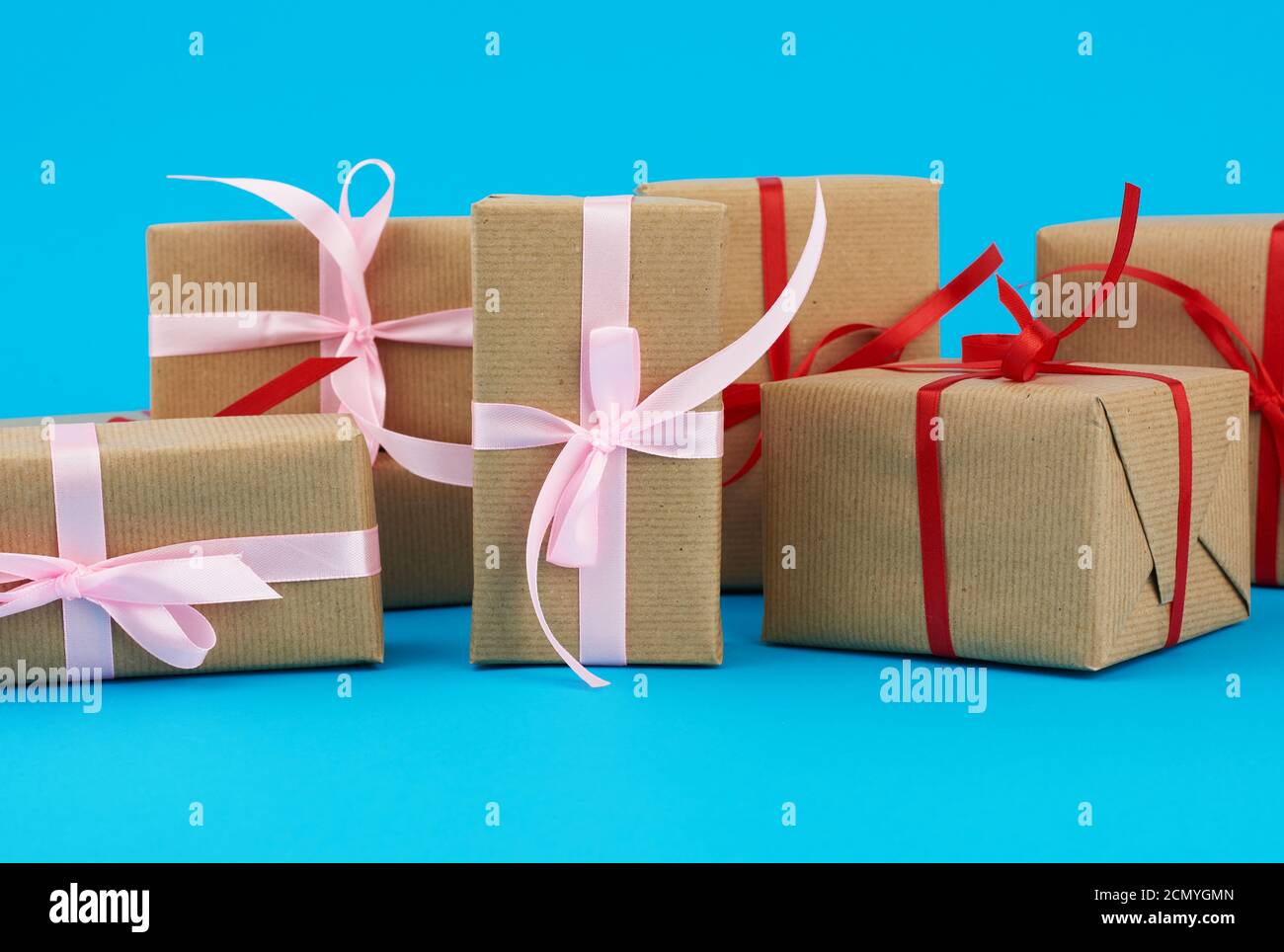 stack of boxes wrapped in brown paper and tied with a red bow, gifts on