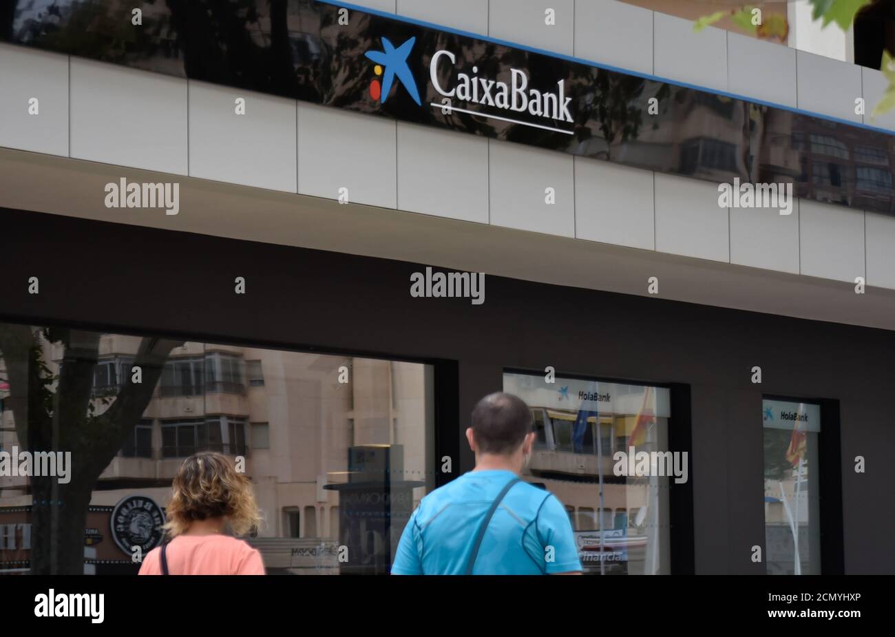 People walk in front of a caixabank branch in Spain.CaixaBank and ...