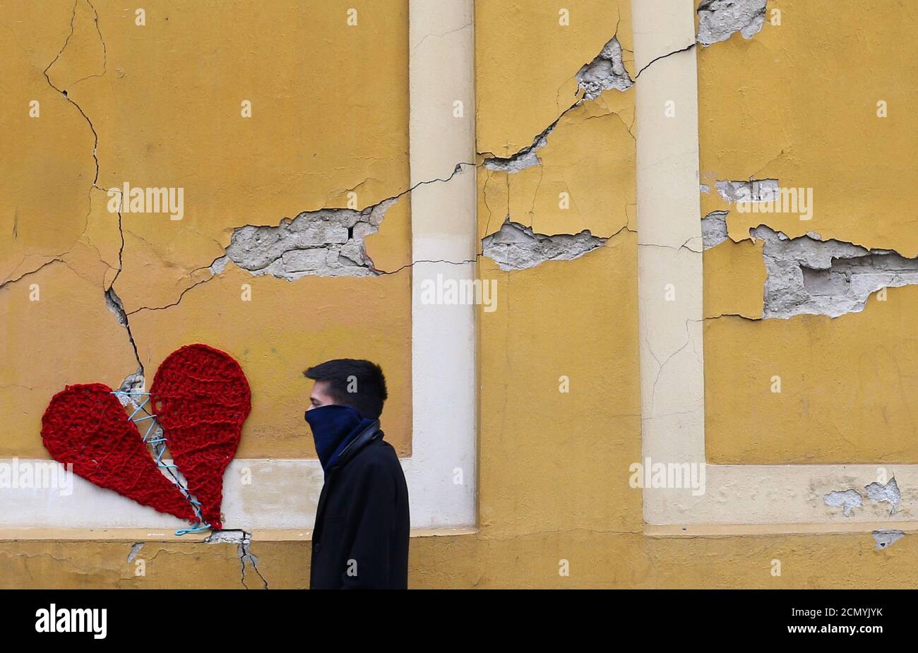 A man walks next to a repaired heart made of wool by Croatian designer Ivona, put on a building in downtown Zagreb, Croatia, March 25, 2020, as the country is fighting