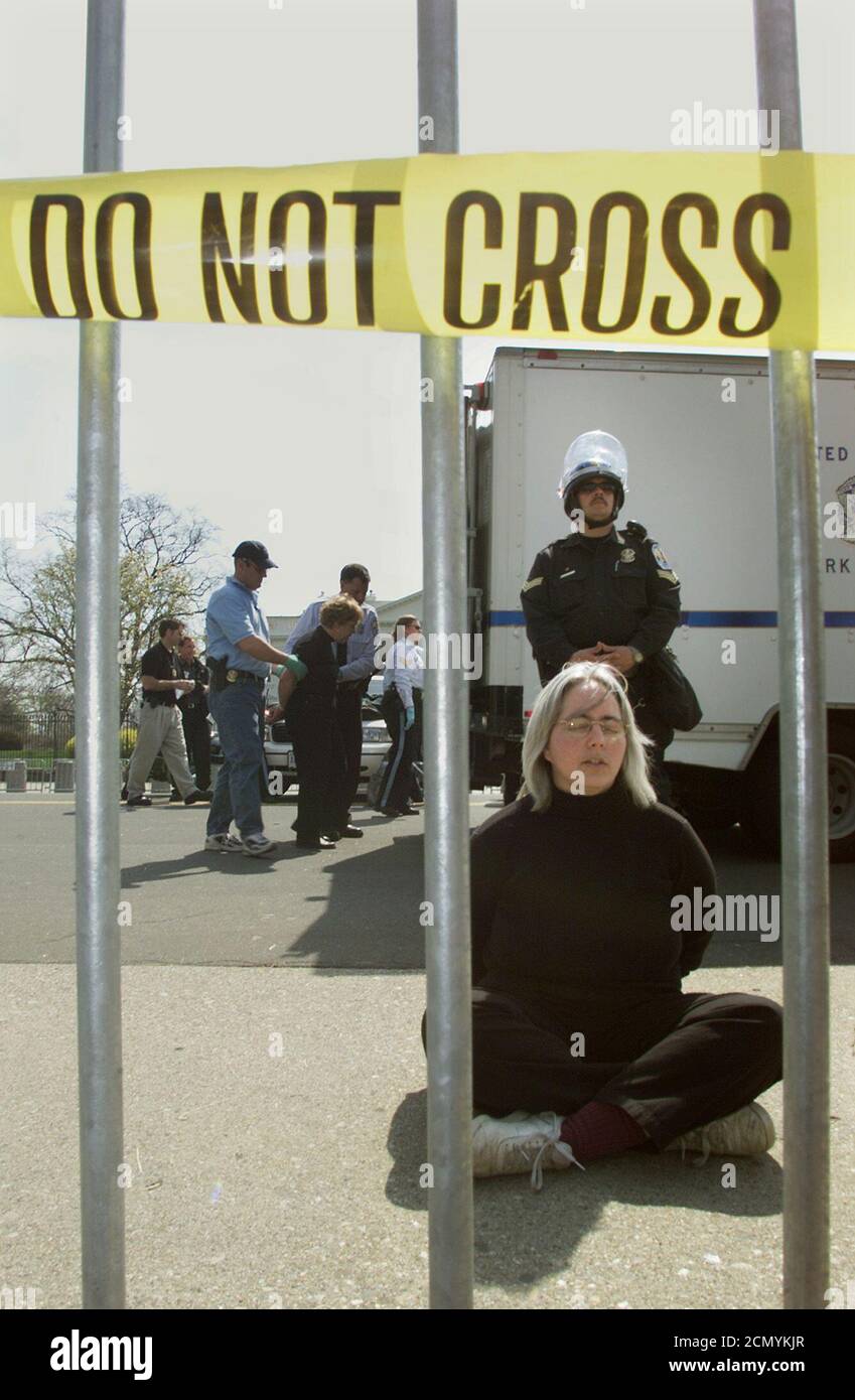 An anti-war protester prays while she sits handcuffed by U.S. Park Police, after jumping a barricade on Pennsylvania Ave. in front of the White House, in Washington March 26, 2003. Police arrested two Nobel Peace prize winners along with more than 60 other people protesting on Wednesday near the White House, as they protested against the U.S.-led war in Iraq. REUTERS/Brendan McDermid  BM/GN Stock Photo