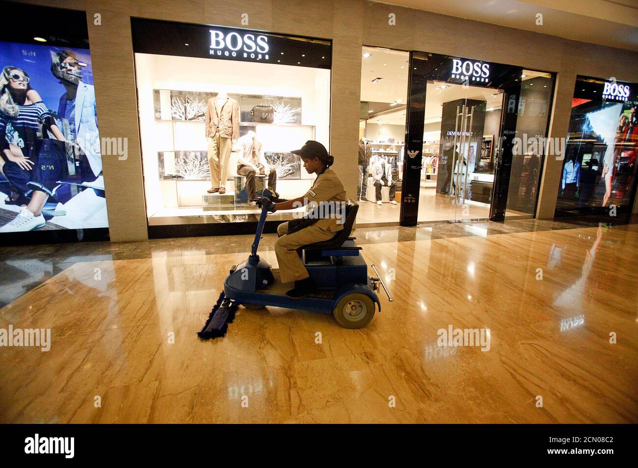 An employee operates a floor cleaning machine in front of a Hugo Boss  showroom inside a shopping mall in Mumbai May 30, 2011. REUTERS/Vivek  Prakash (INDIA - Tags: BUSINESS EMPLOYMENT Stock Photo - Alamy