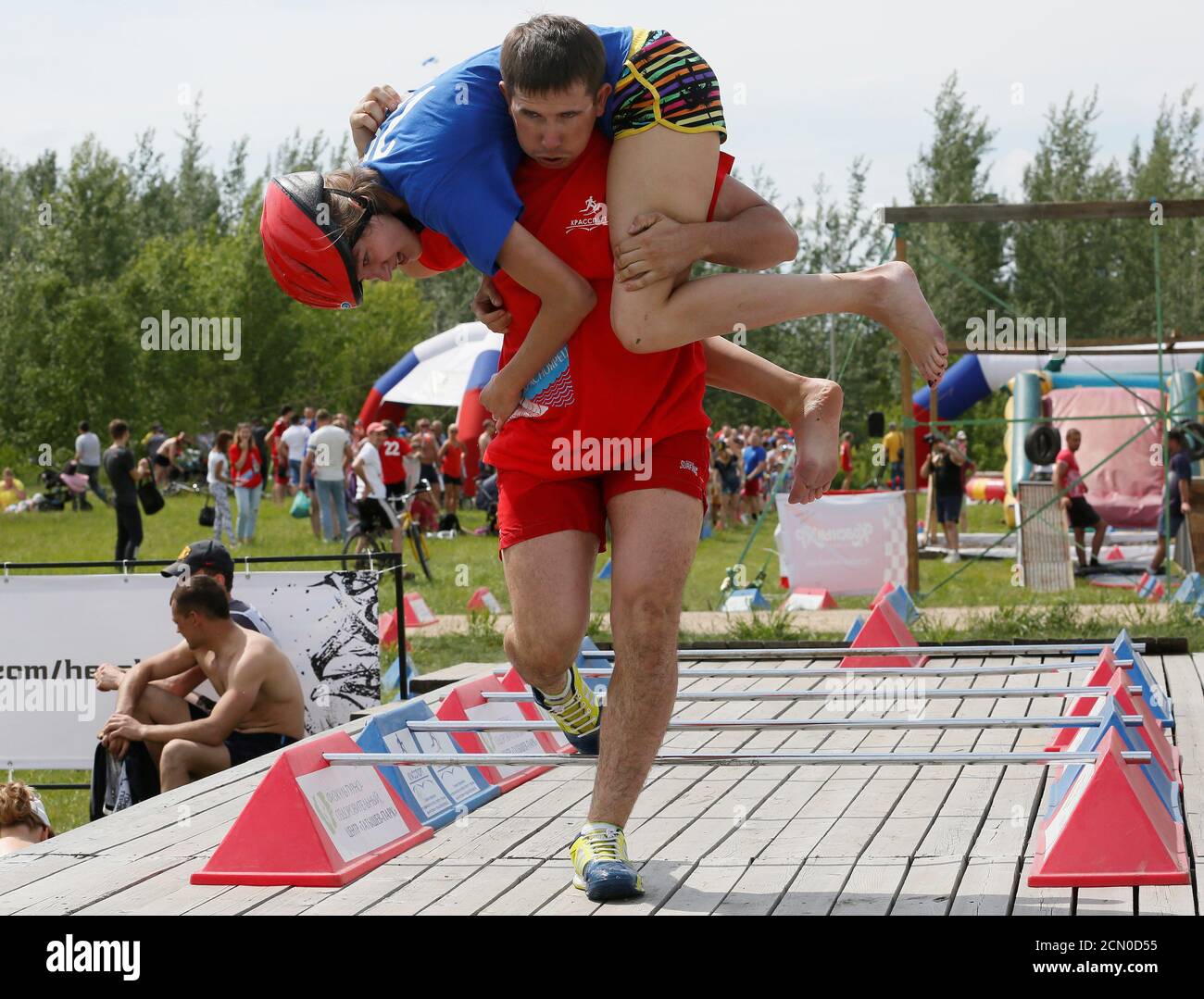 A man carries his wife over an obstacle while racing in the Wife Carrying competititon to mark the City Day in Krasnoyarsk, Siberia, Russia, June 10, 2017. Picture taken June 10, 2017. REUTERS/Ilya Naymushin Stock Photo