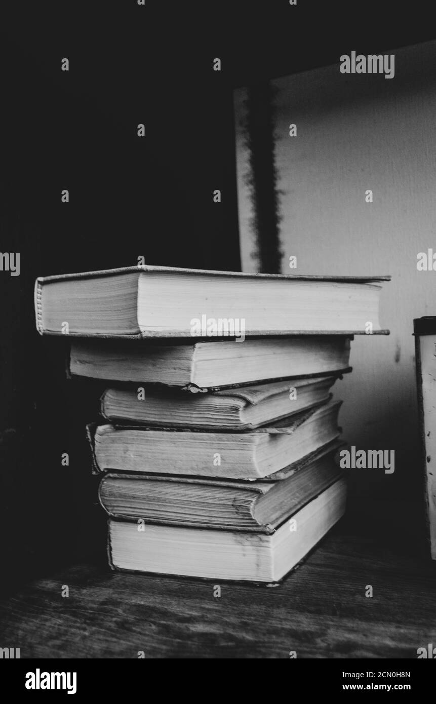 Black and white filter on a group of books stacked on a shelf. Stock Photo