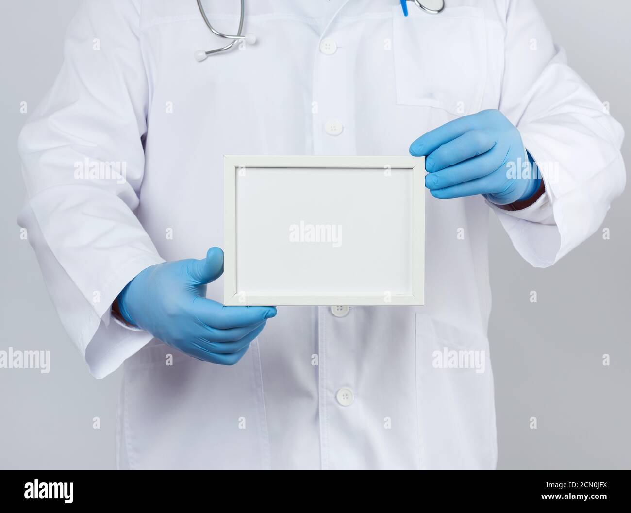 male doctor in a white medical coat and blue latex gloves holds an ...