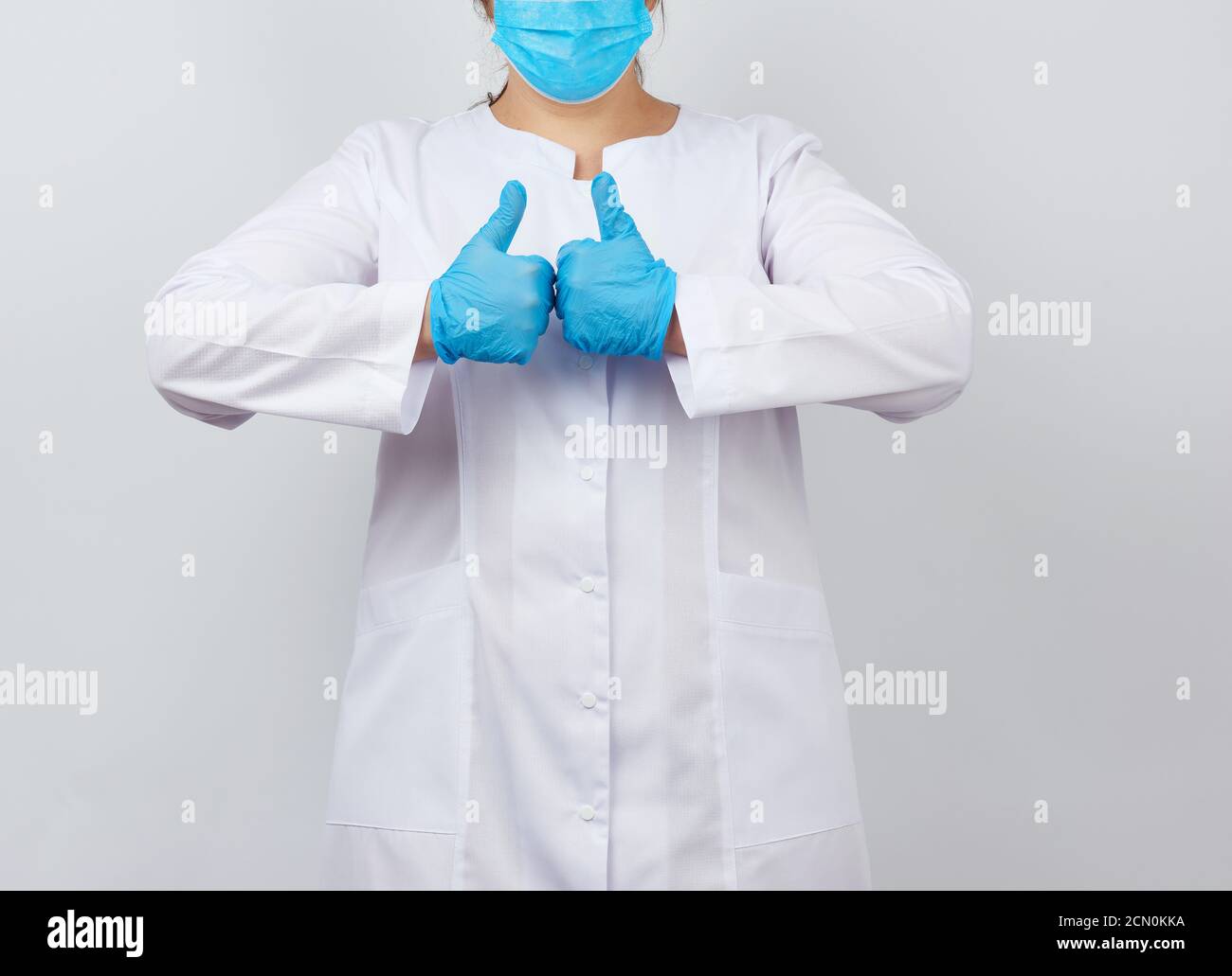 medic woman in white coat and mask, wearing blue medical latex gloves ...