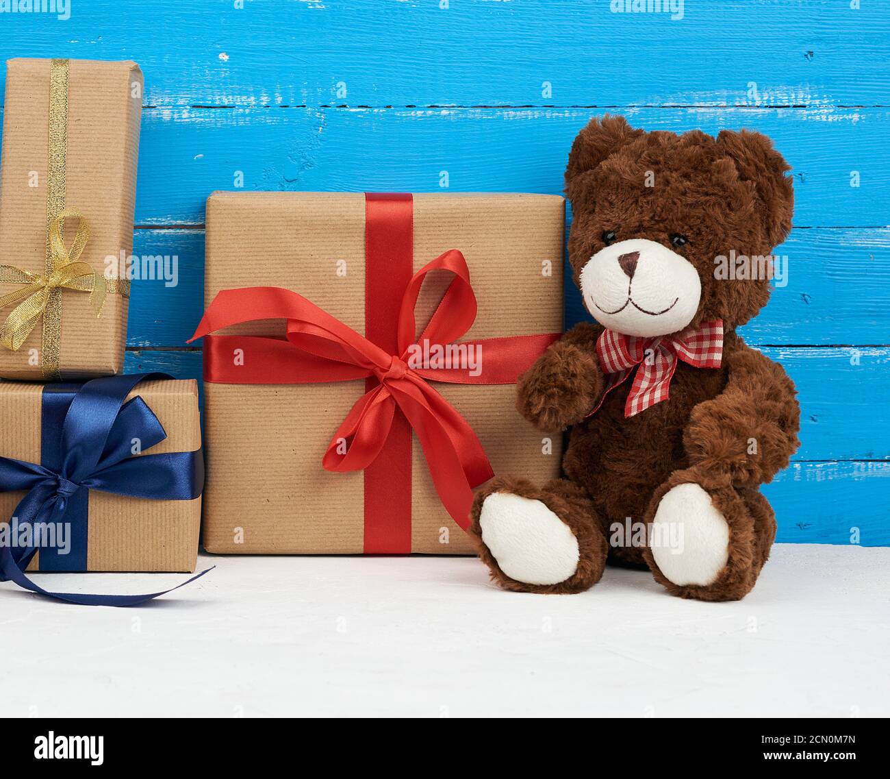 cute brown teddy bear sits on a blue wooden background and gift box ...
