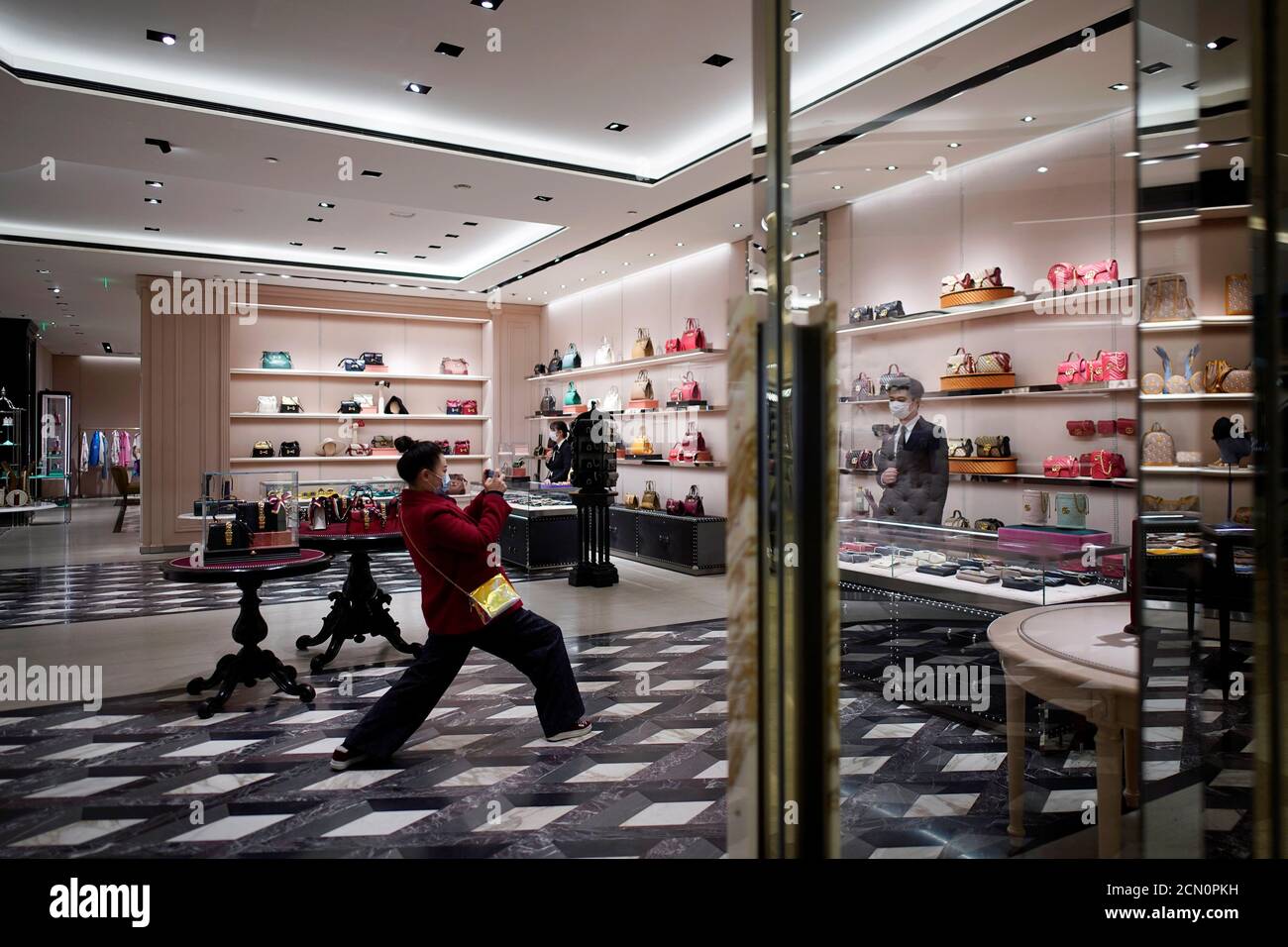 A staff member wearing a face mask poses for pictures at a Gucci store  inside a shopping mall in Wuhan, Hubei province, the epicentre of China's  coronavirus disease (COVID-19) outbreak, March 30,