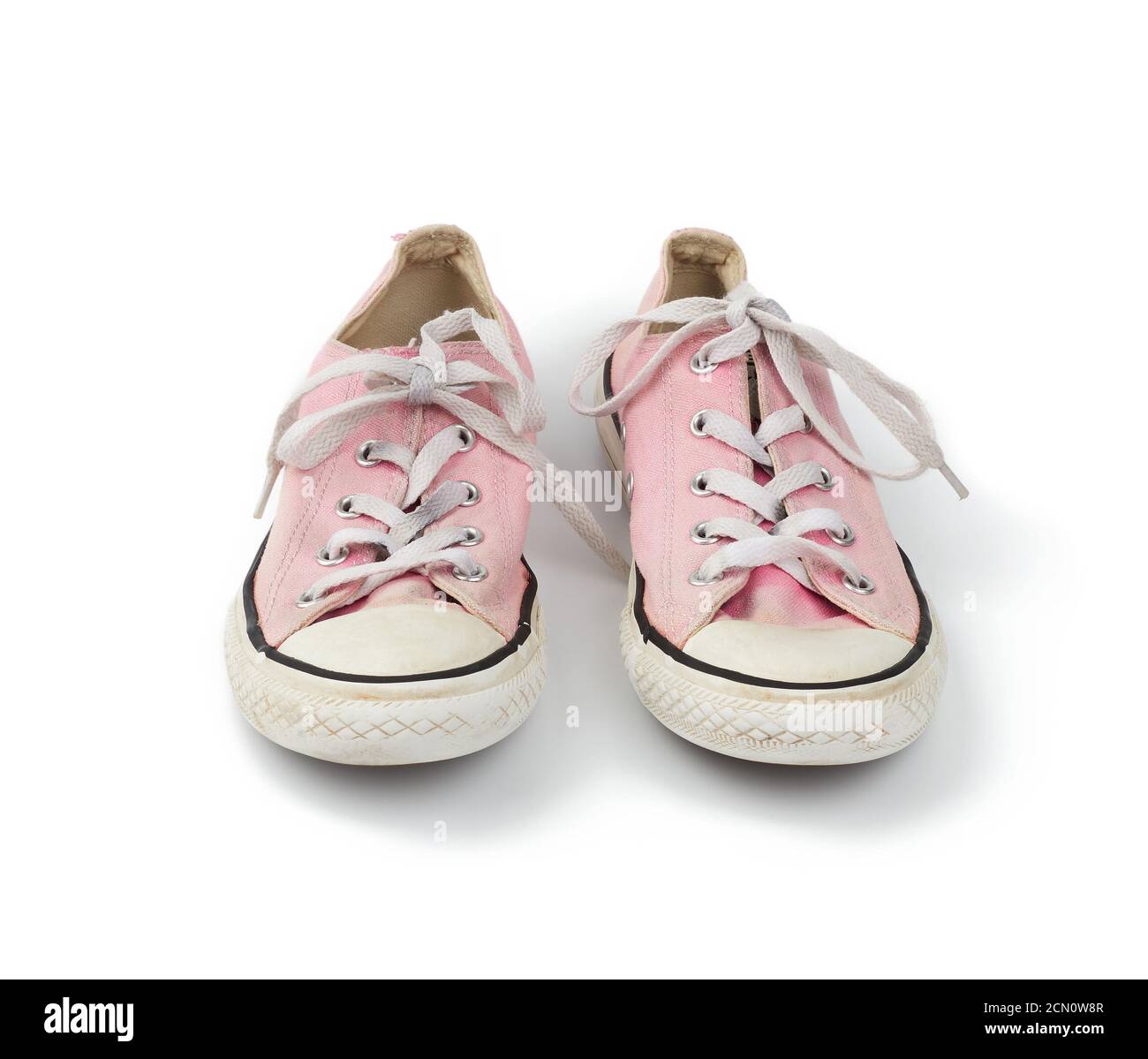 pair of light pink worn textile sneakers with laces isolated on a white ...