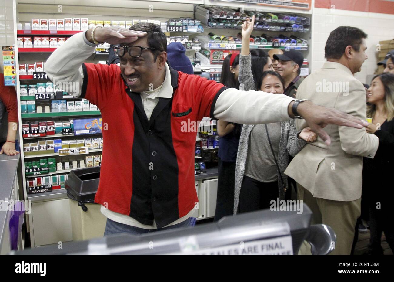 7-Eleven store clerk M. Faroqui celebrates after selling a winning Powerball ticket, in Chino Hills, California January 13, 2016. A winning ticket was sold there for the massive $1.59 billion Powerball lottery on Wednesday, officials said after drawing the winning numbers for the world's largest potential jackpot for a single player. REUTERS/Alex Gallardo Stock Photo