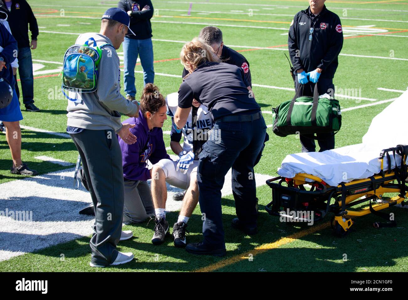 Paramedics carefully placing hurt high school football player on rolling gurney. St Paul Minnesota MN USA Stock Photo