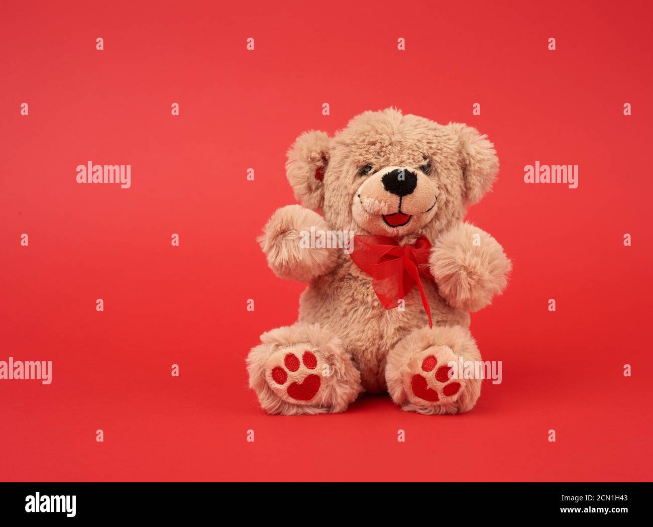 Cute Little Brown Teddy Bear Toy Is Sitting On A Red Background Stock Photo Alamy