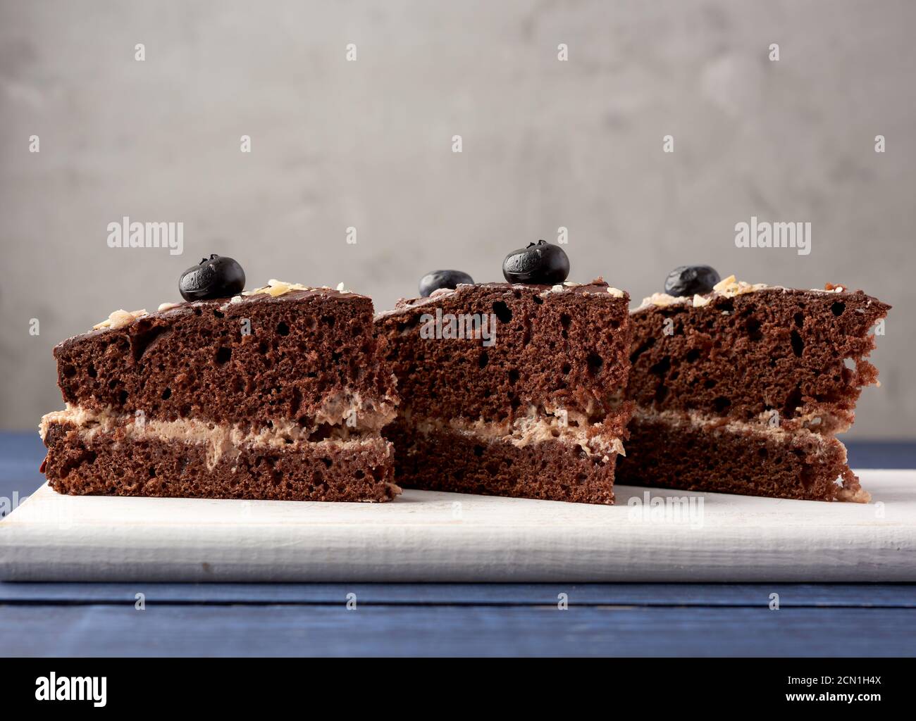 three triangular pieces of chocolate biscuit cake with butter cream on ...