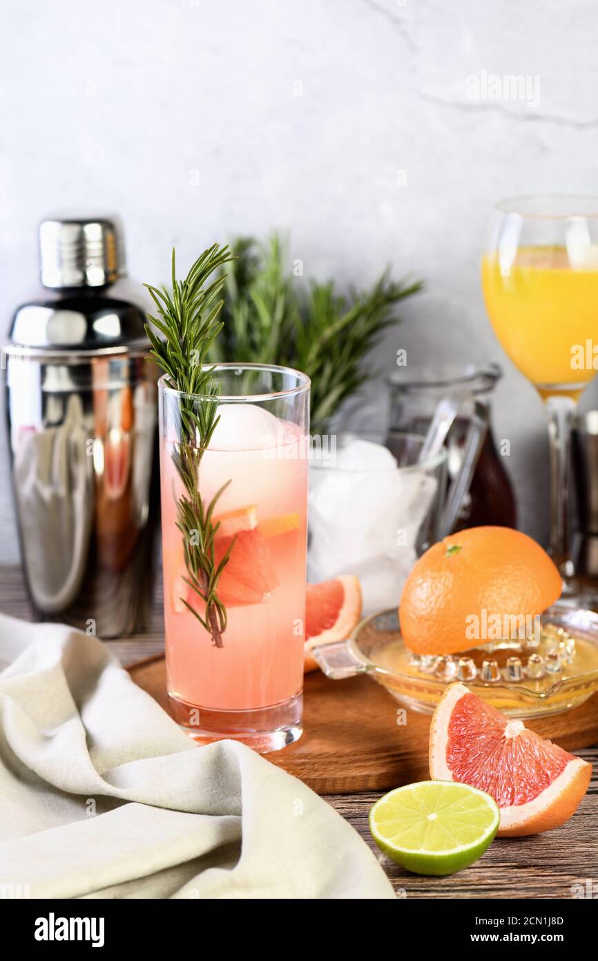 Gin cocktail with rosemary and pomegranate on a table among citrus